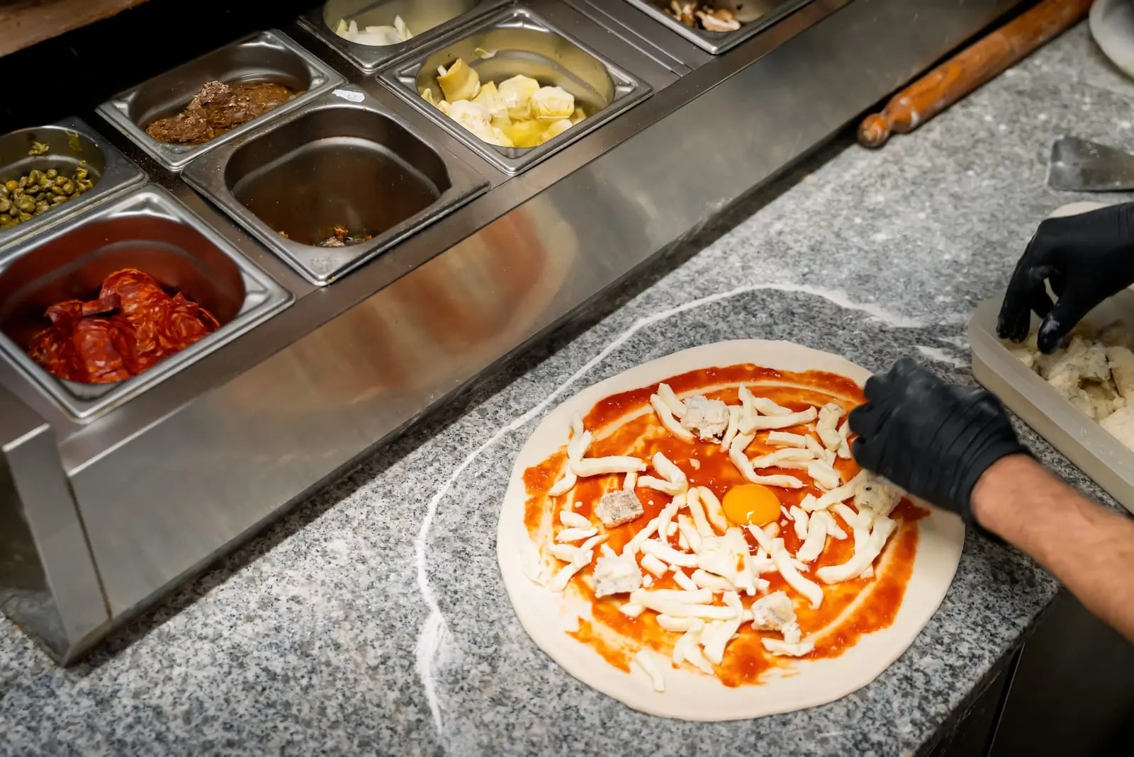Garniture minute d'une pizza au comptoir · cuisine du restaurant italien Little Italy Menton